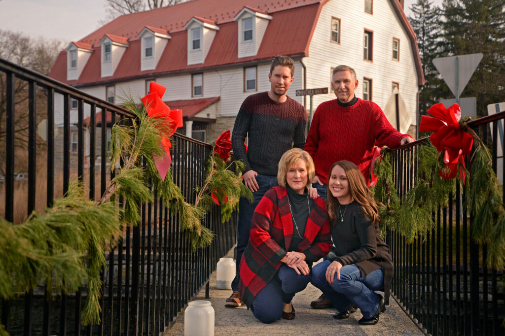 Family in Christmas sweaters in front of old Mill