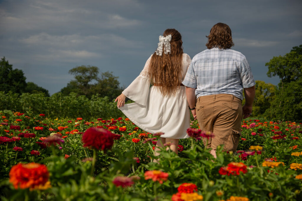 Emily and Michael walking through flower field